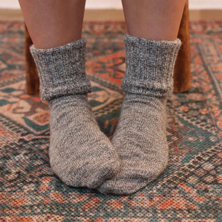Gray socks worn on a patterned rug