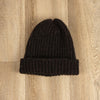 Black knit beanie on a wooden surface