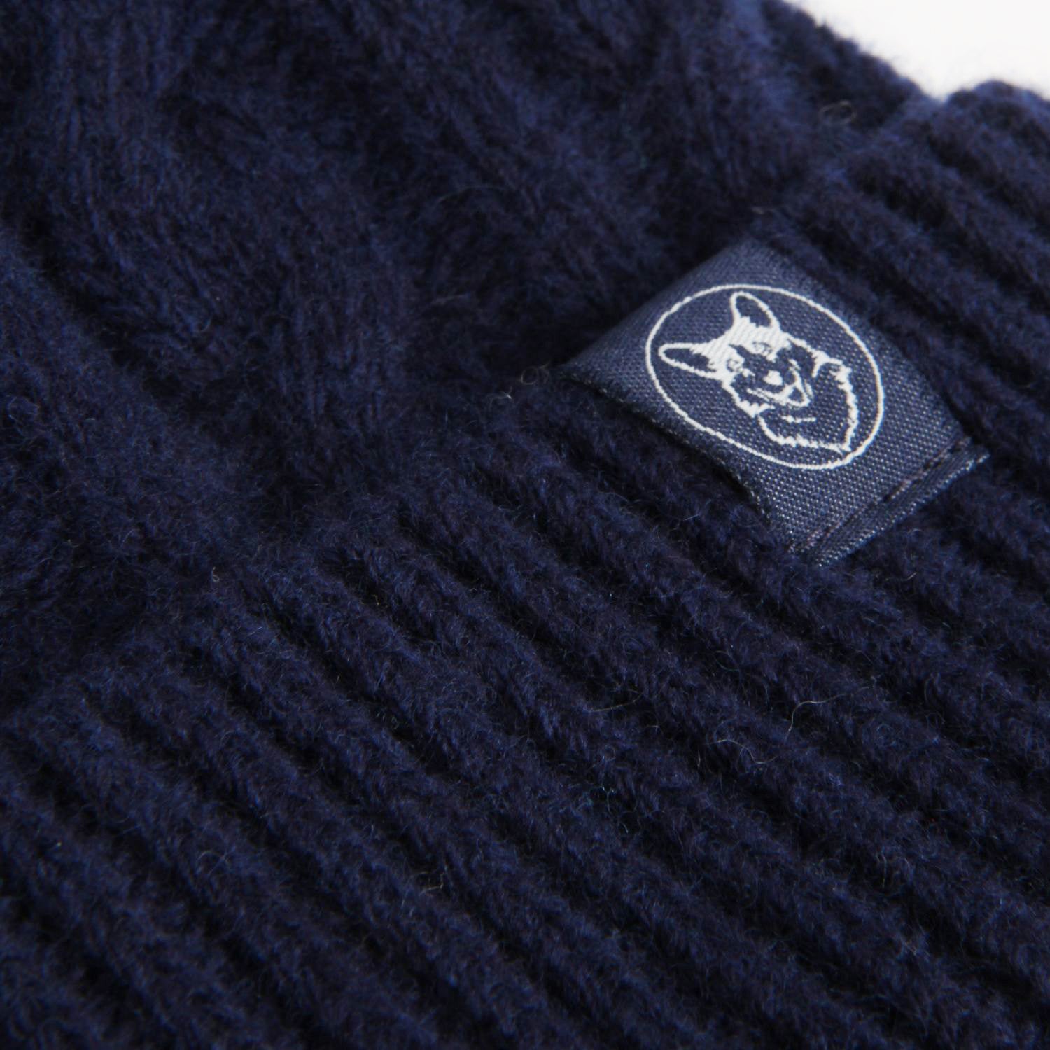 Navy blue knit fabric with a brand logo tag featuring a Corgi dog face.