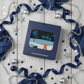 Box of luxury socks with a design of two people skiing on a blue background, made in Wales, UK.