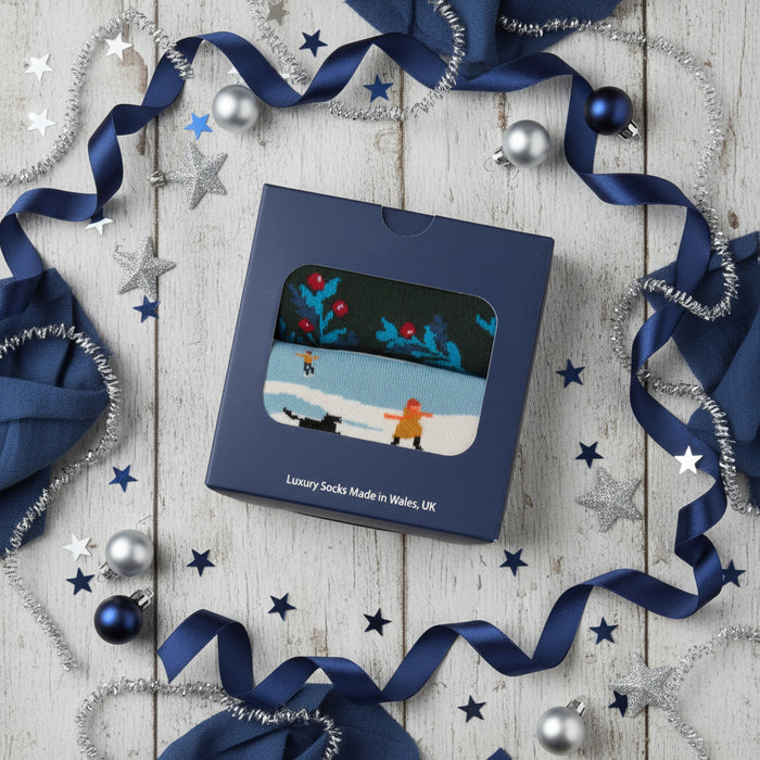 Box of luxury socks with a design of two people skiing on a blue background, made in Wales, UK.
