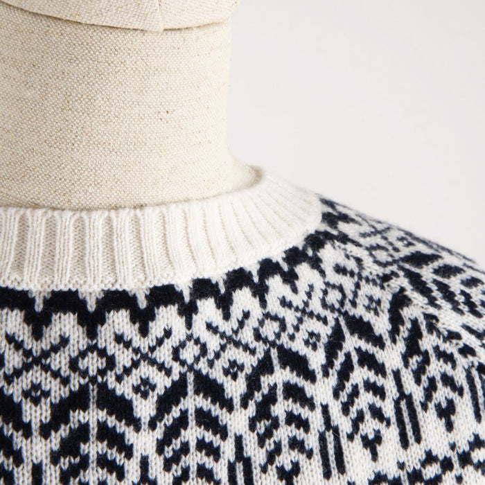 Close-up of a sweater with a navy and white pattern on a neutral background