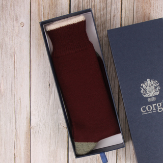 Maroon sock in an open box with a visible brand logo on a wooden surface