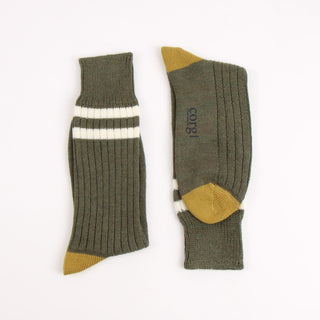 Pair of green socks with two white striped and mustard yellow accents on the heel and toe, photographed on a white background