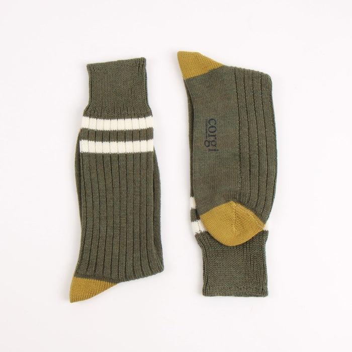 Pair of green socks with two white striped and mustard yellow accents on the heel and toe, photographed on a white background