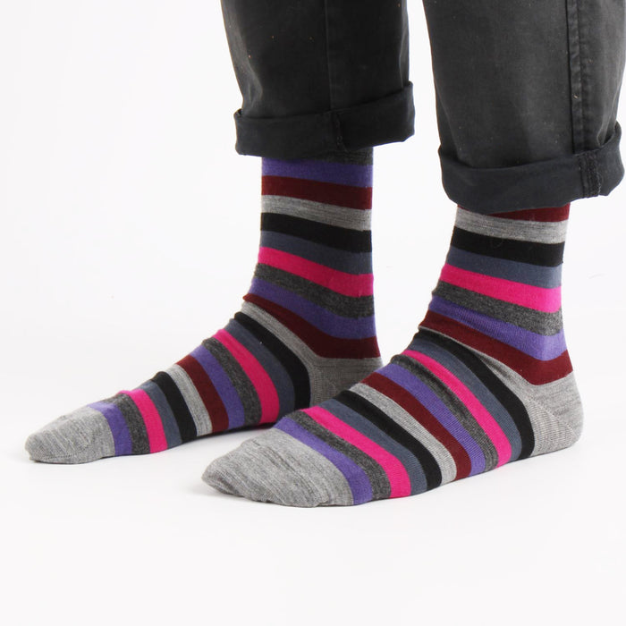 Striped socks with purple, gray, and pink colors worn by a person on a white background