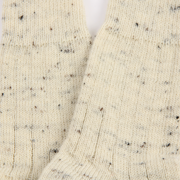 Close-up of a textured beige fabric with black specks