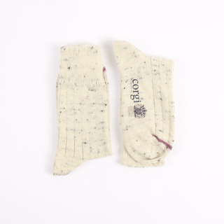 Pair of cream-colored socks with speckles on a white background, featuring the brand 'corgi'.