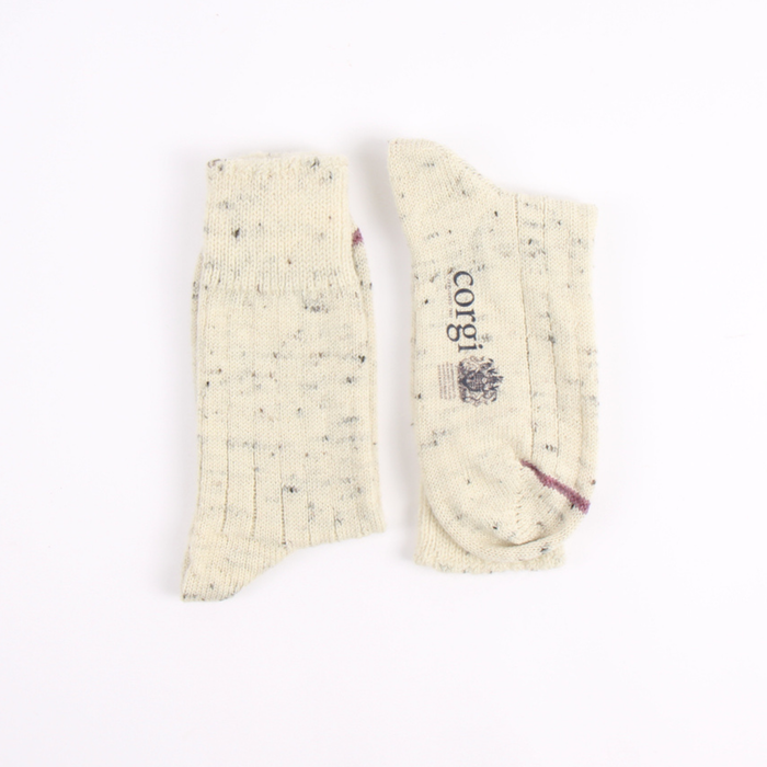 Pair of cream-colored socks with speckles on a white background, featuring the brand 'corgi'.