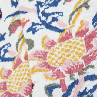 Close-up of a floral fabric pattern with pink, yellow, and blue colors on a white background.