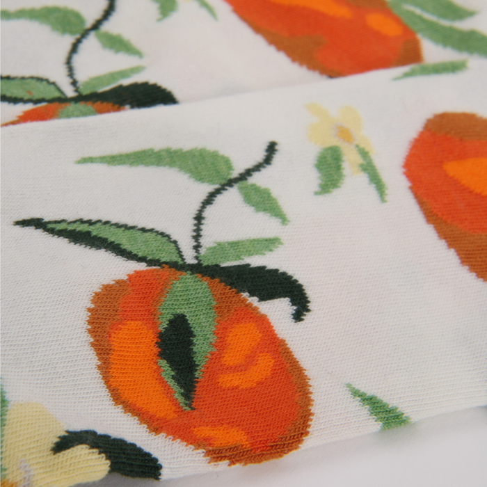 Close-up of fabric showing oranges and leaves on a white backgroundnd