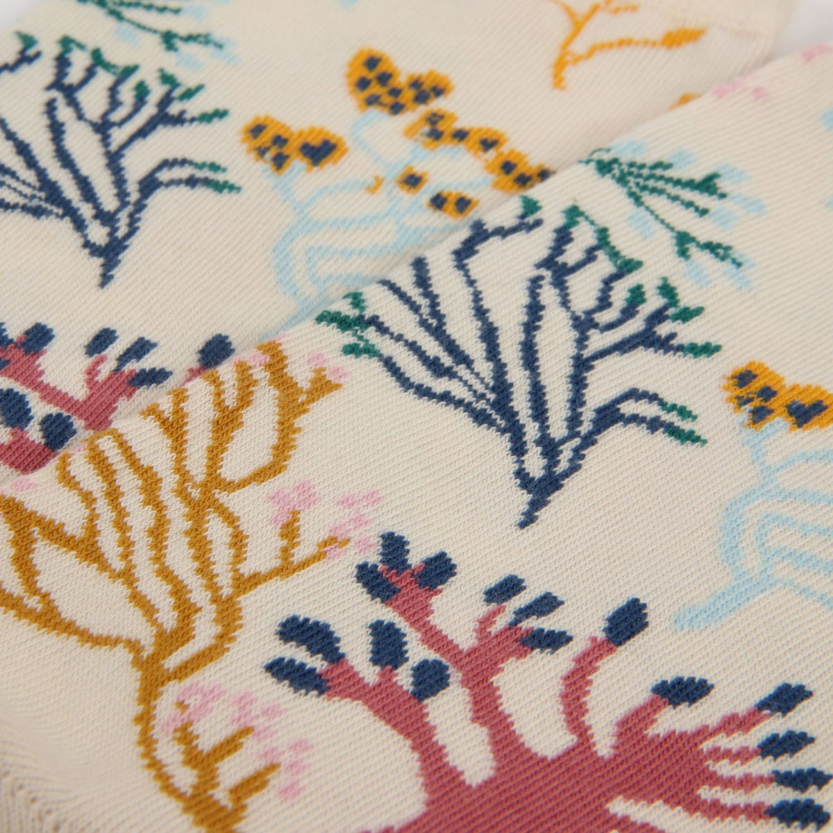Close-up of a fabric with colorful coral reef pattern on a beige background