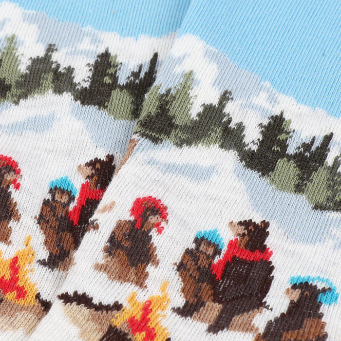 Socks with bear design sitting around a campfire in a snowy landscape.