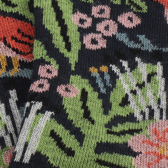 close up of the knitted sock fabric with a jungle-themed pattern including colourful plants, flowers, and animals like leopards and birds on a navy background.
