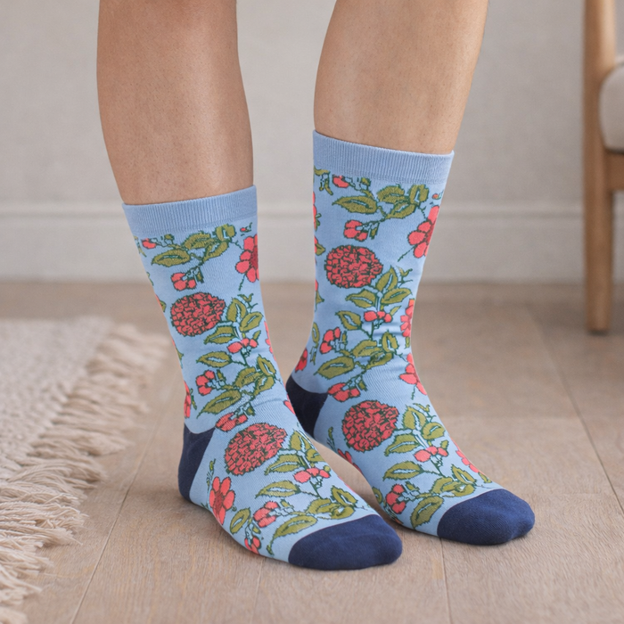 Floral patterned socks worn by a person on a wooden floor.