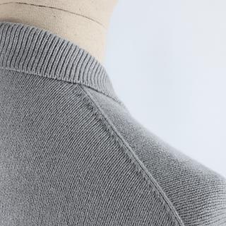 Close-up of a gray sweater on a mannequin with a light blue background