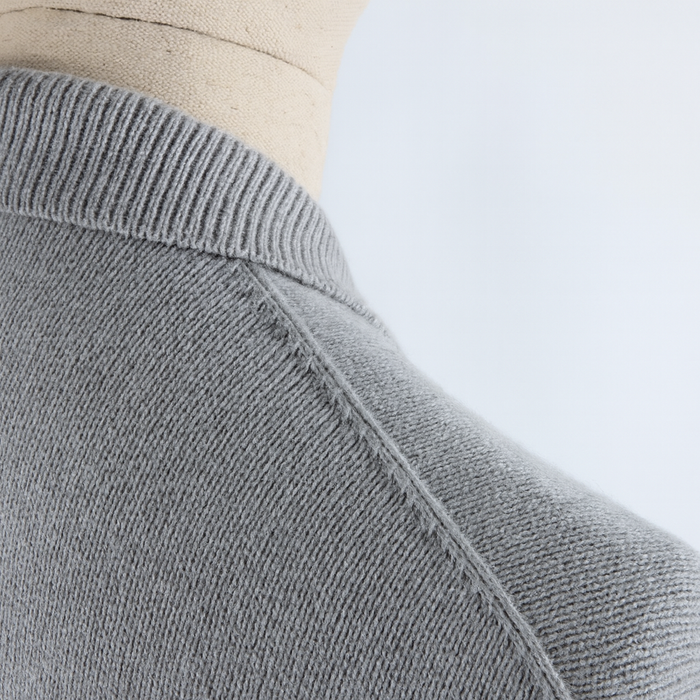Close-up of a gray sweater on a mannequin with a light blue background