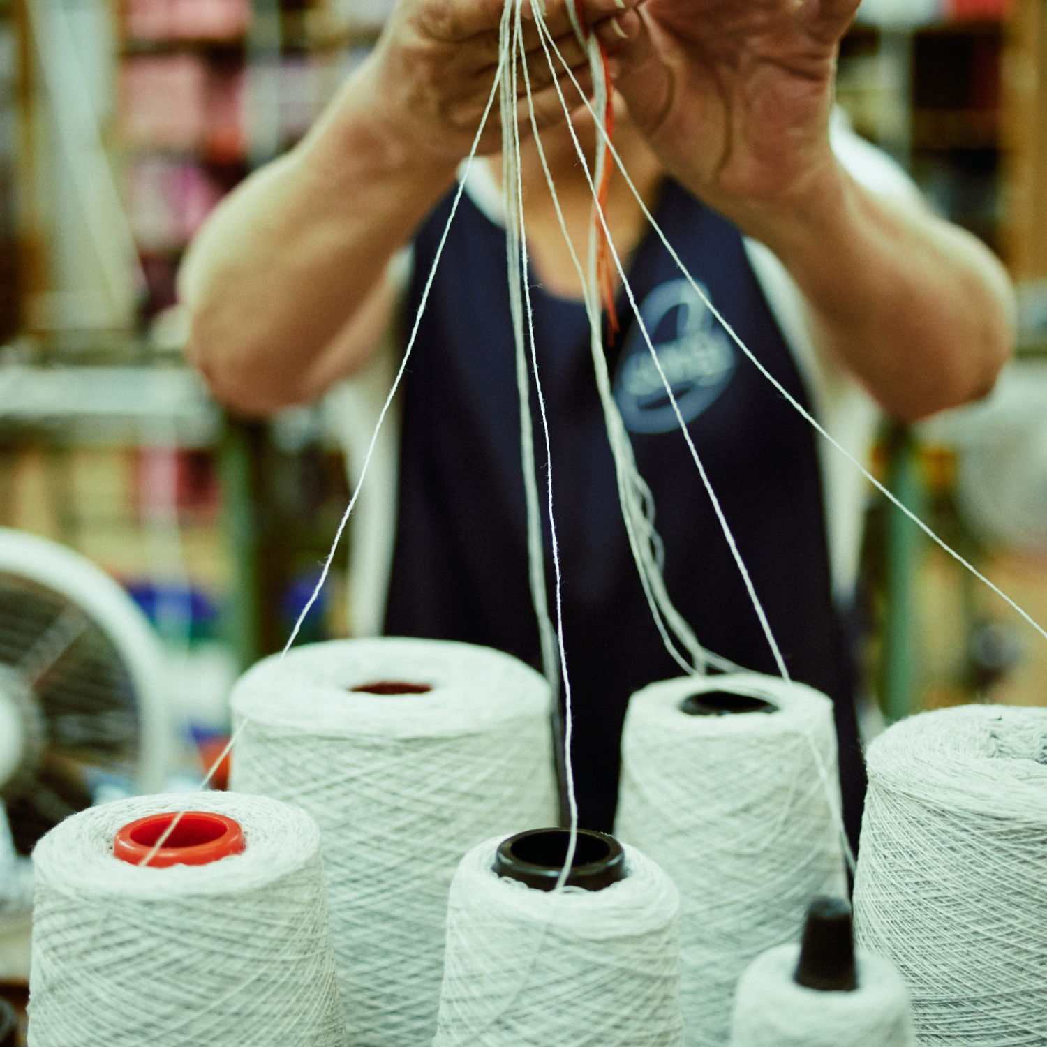 Person handling yarn with spools in the foreground