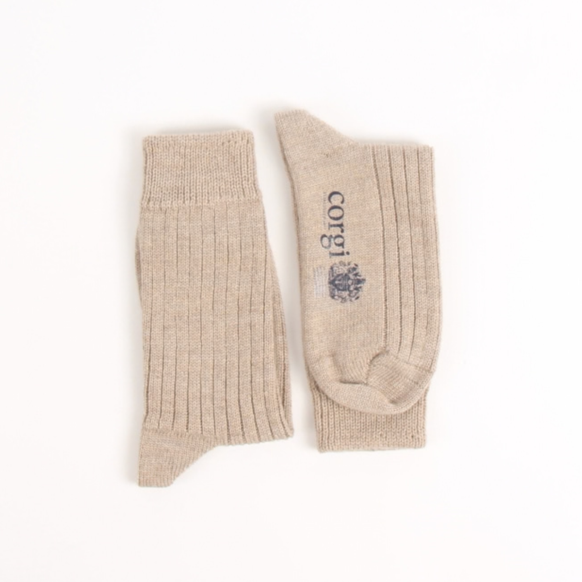 A pair of ribbed knit crew socks in a light beige/tan color, featuring a dark navy logo and text on the sole, displayed against a solid white background.