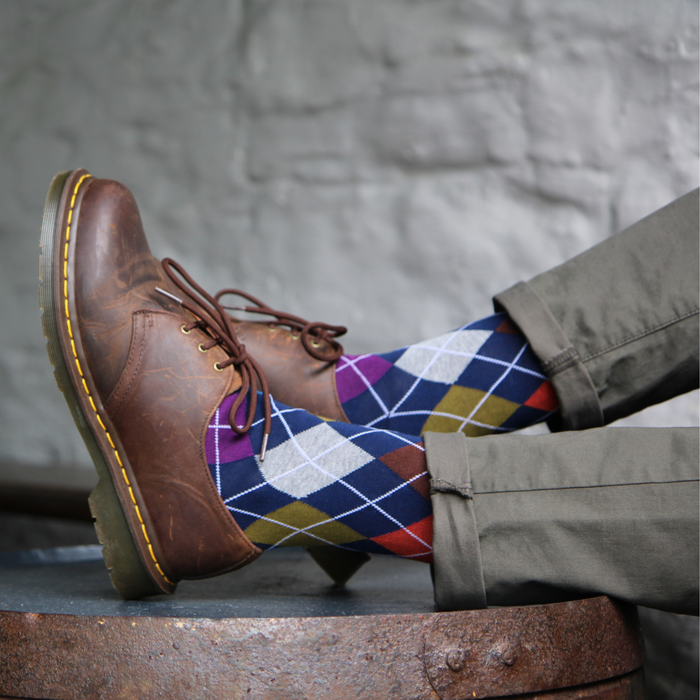Brown leather shoes with an argyle patterned sock against a neutral background
