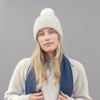 person wearing Beige knit beanie with a grey pom-pom on a grey  background