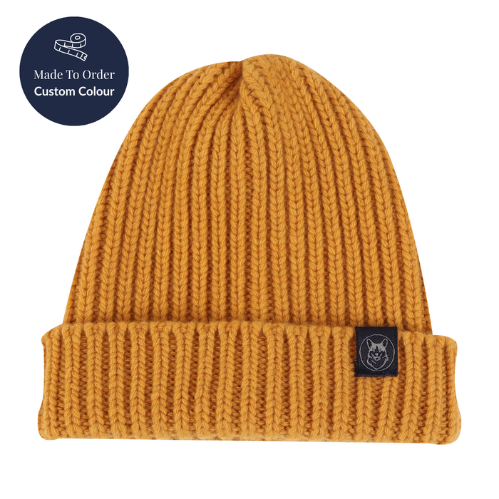 Mustard yellow knit beanie with a brand logo on a white background
