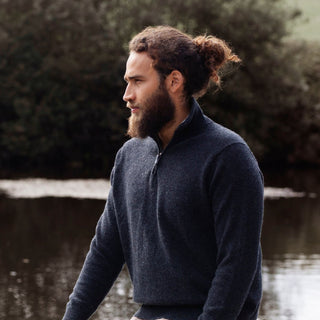 A man wearing a navy blue half zip sweater with a unique contrasting colour collar, standing outdoors.