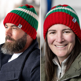 Two adults, one male and one female, wearing a red, green, and white striped wool beanie hat.
