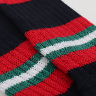Close-up of a knitted fabric with red, green, and white stripes on a black background.