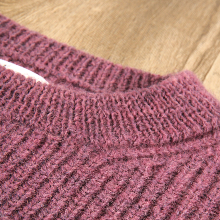 Close-up of a textured pink knitted fabric on a wooden surface
