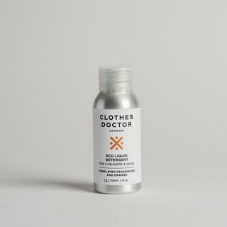 A travel-sized 50ml bottle of Cashmere & Wool detergent by The Clothes Doctor, with a white label and orange accents, on a light background.