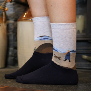 Person wearing socks with scenic beach scene socks in a home setting