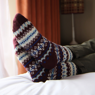 Pair of patterned socks being worn on a bed with a blurred background