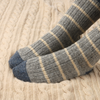 Pair of pale blue socks with off white stripes on a textured surface