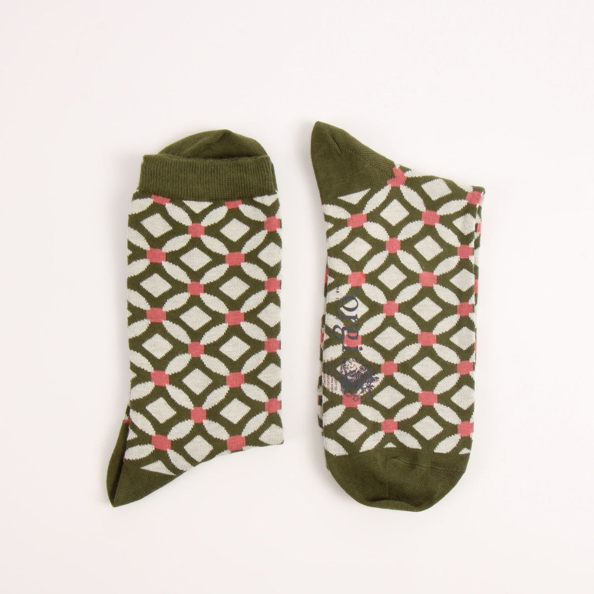 Close-up of a knitted fabric with an interlocking geometric pattern in olive green, off-white, and pink.