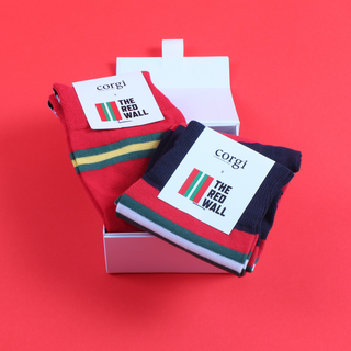 A pair of red, blue, and white striped cotton socks with the text 'THE RED WALL' on the heel, displayed in an open white box on a red background.