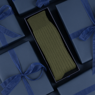 Loden green cashmere socks in a navy box with blue ribbons on a dark background