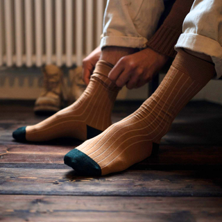 Person wearing striped socks on a wooden floor with a radiator in the background