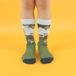 A pair of patterned cotton socks featuring a cricket scene with players on a green field, designed for children.