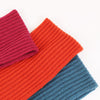 Three knitted scarves in red, orange, and blue on a white background