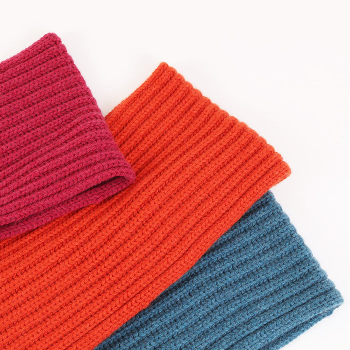 Three knitted scarves in red, orange, and blue on a white background
