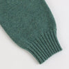 Close-up of a green knitted sleeve on a white background