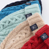 Stack of knitted beanies in blue, green, beige, and red with brand tags.