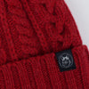 Close-up of a red knitted item with a brand label featuring a corgi logo.