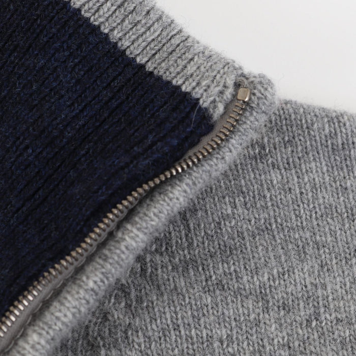 Close-up of a gray and navy zip-up garment on a light gray background