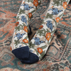 person wearing William Morris trellis design socks on a patterned rug