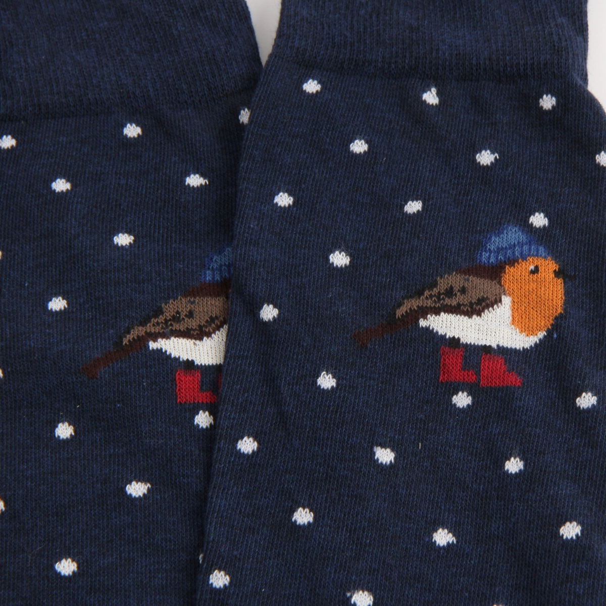 A close-up of a pair of navy blue knit socks with a winter robin design and white snowflakes. The robin is patterned with brown, orange, white, blue, and red details.