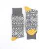 Pair of gray socks with white snowflake pattern and yellow tips on a white background