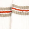Close-up of a sock with horizontal stripes in beige, orange, and white on a white background