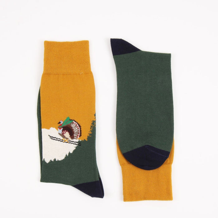 Two socks with a design of a turkey skiing on a mountain, photographed on a white background.